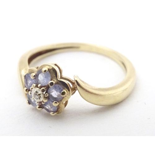 572 - A 9ct gold ring set with central diamond bordered by five tanzanite stones. Ring size approx. N 1/2