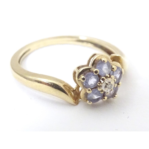 572 - A 9ct gold ring set with central diamond bordered by five tanzanite stones. Ring size approx. N 1/2