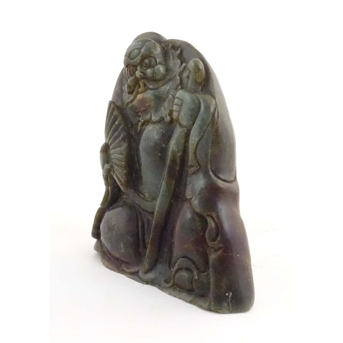 1021 - A Chinese carved jade figure depicting a man holding a fan and a staff. Approx. 6 1/4