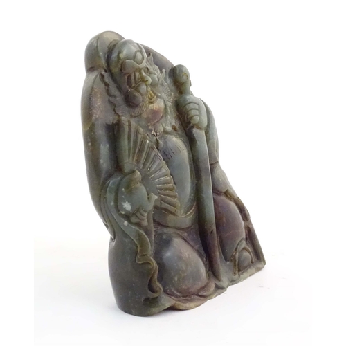 1021 - A Chinese carved jade figure depicting a man holding a fan and a staff. Approx. 6 1/4