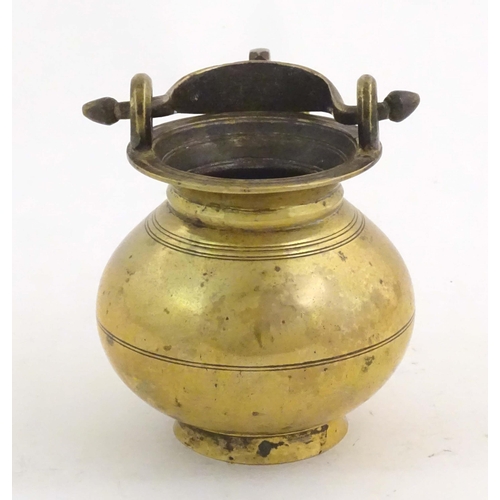 1023 - A brass water pot with bulbous body and swing handle with hanging loop and incised banded decoration... 