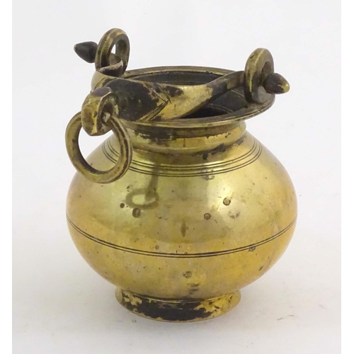 1023 - A brass water pot with bulbous body and swing handle with hanging loop and incised banded decoration... 