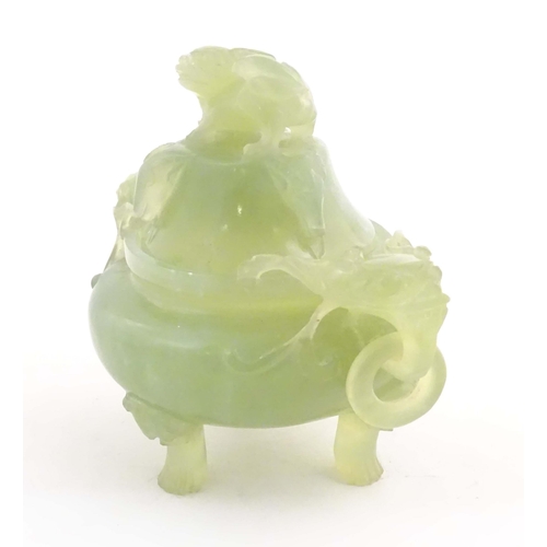 1026 - A Chinese carved light jade coloured hardstone censer and cover raised on three feet, with twin hand... 