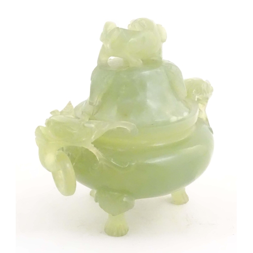 1026 - A Chinese carved light jade coloured hardstone censer and cover raised on three feet, with twin hand... 