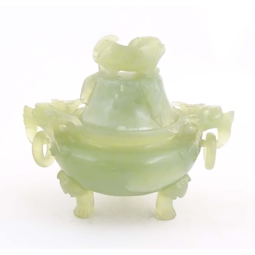 1026 - A Chinese carved light jade coloured hardstone censer and cover raised on three feet, with twin hand... 