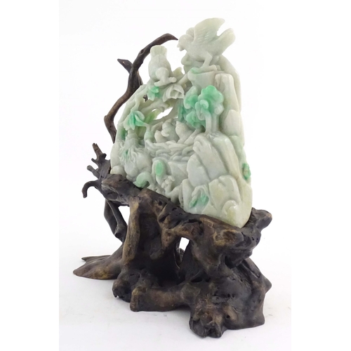 1027 - A Chinese light jade coloured hardstone 'boulder' carving depicting birds feeding chicks in a nest a... 