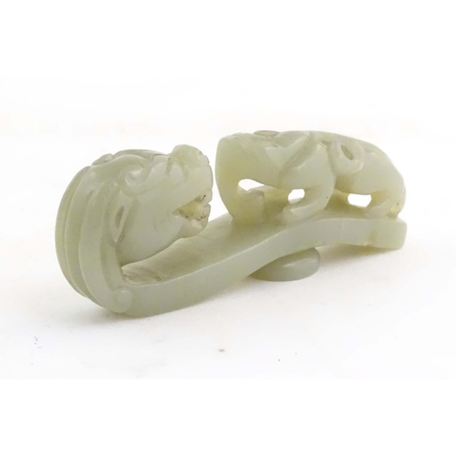 1040 - A Chinese light jade coloured hardstone carved belt hook depicting a dragon head and stylised chilon... 