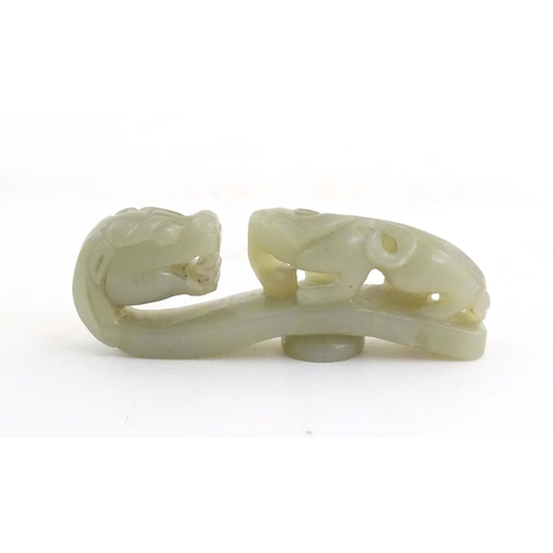 1040 - A Chinese light jade coloured hardstone carved belt hook depicting a dragon head and stylised chilon... 