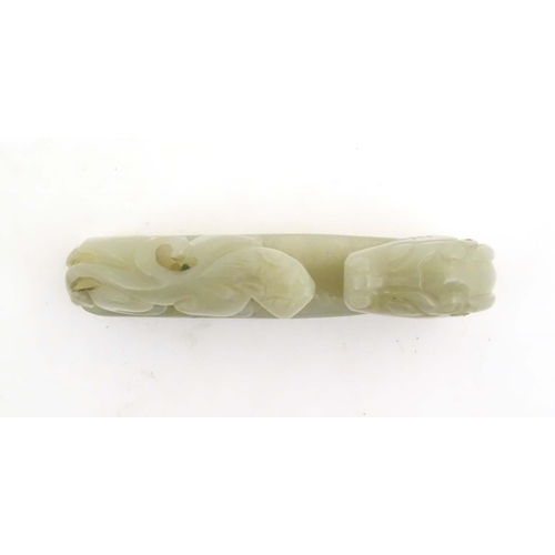 1040 - A Chinese light jade coloured hardstone carved belt hook depicting a dragon head and stylised chilon... 