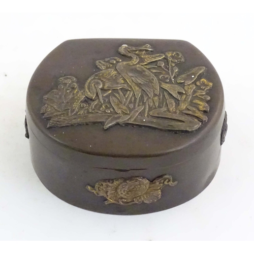 1051 - A Japanese lacquered brass stud box with a hinged lid, decorated with applied crane bird and floral ... 