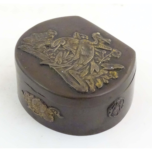 1051 - A Japanese lacquered brass stud box with a hinged lid, decorated with applied crane bird and floral ... 