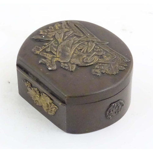 1051 - A Japanese lacquered brass stud box with a hinged lid, decorated with applied crane bird and floral ... 