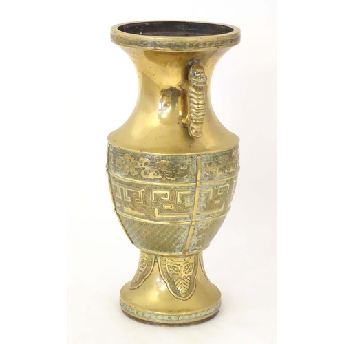 1279 - An Oriental cast brass vase of baluster form with twin foo dog handles, the body decorated with styl... 