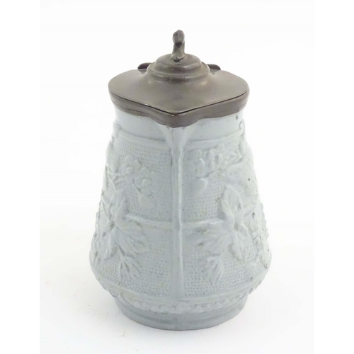 1098 - A Victorian stoneware jug with a pewter lid, the body with moulded decoration depicting birds, flowe... 