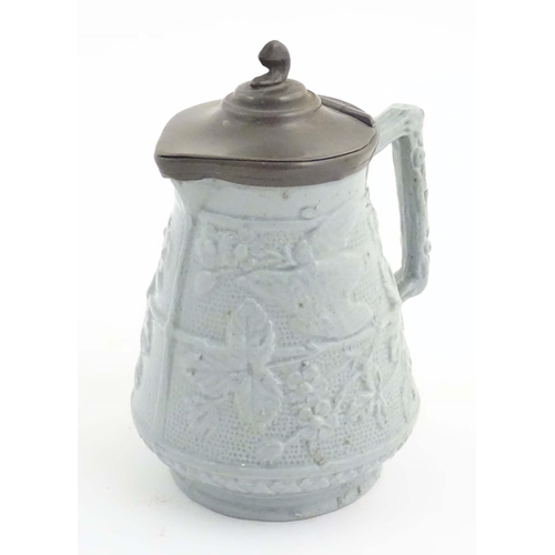 1098 - A Victorian stoneware jug with a pewter lid, the body with moulded decoration depicting birds, flowe... 