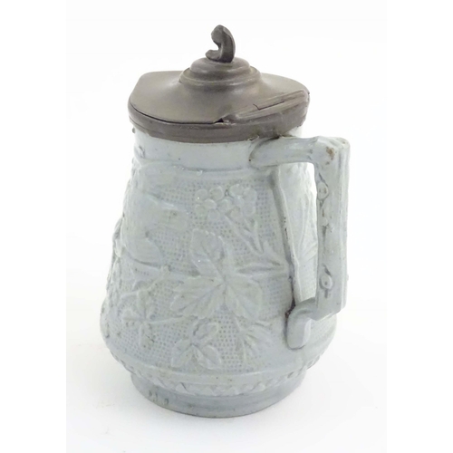 1098 - A Victorian stoneware jug with a pewter lid, the body with moulded decoration depicting birds, flowe... 