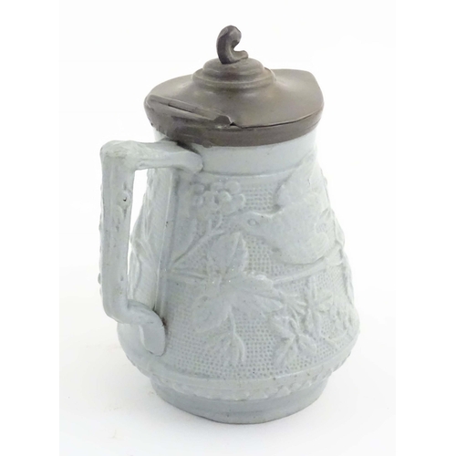 1098 - A Victorian stoneware jug with a pewter lid, the body with moulded decoration depicting birds, flowe... 