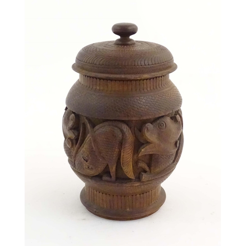 1131 - A Chinese wooden tobacco jar / pot and cover with carved decoration depicting stylised fish. Approx.... 