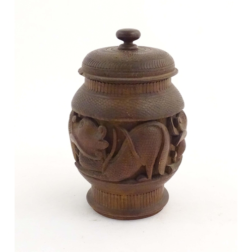 1131 - A Chinese wooden tobacco jar / pot and cover with carved decoration depicting stylised fish. Approx.... 