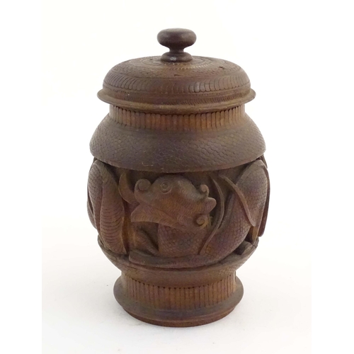 1131 - A Chinese wooden tobacco jar / pot and cover with carved decoration depicting stylised fish. Approx.... 