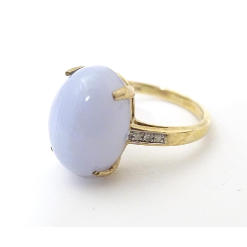 577 - A 9ct gold dress ring set with lace agate cabochon flanked by three diamonds to each shoulder. Ring ... 