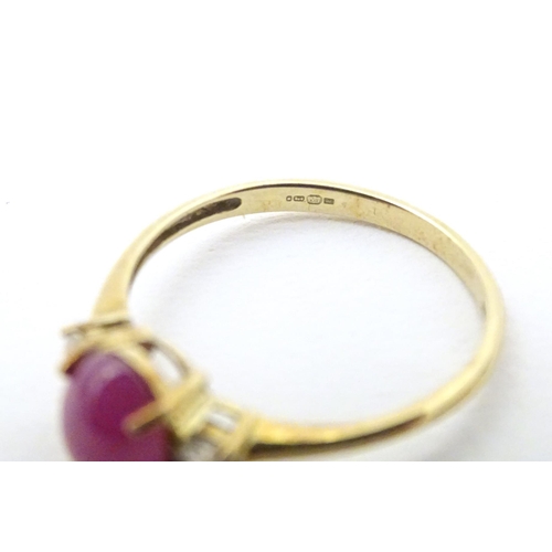 578 - A 9ct gold ring with ruby coloured cabochon flanked by two white stones. Ring size approx. N 1/2