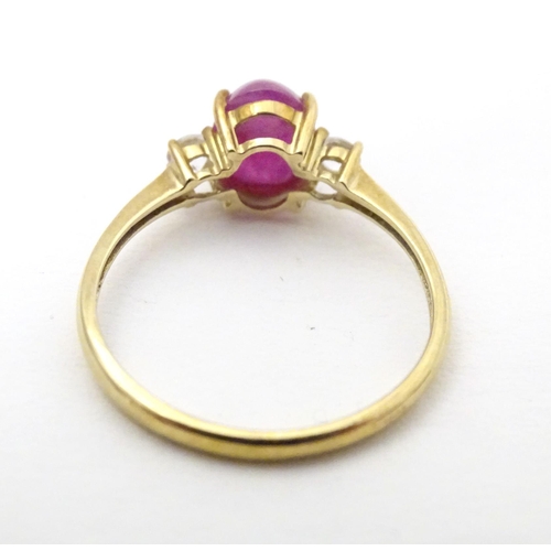 578 - A 9ct gold ring with ruby coloured cabochon flanked by two white stones. Ring size approx. N 1/2