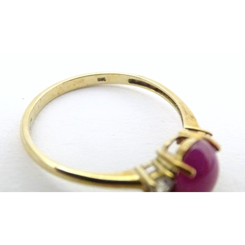 578 - A 9ct gold ring with ruby coloured cabochon flanked by two white stones. Ring size approx. N 1/2