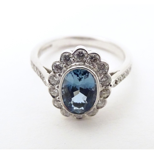 579 - A 9ct white gold ring set with aquamarine coloured oval stone to centre bordered by diamonds with fu... 