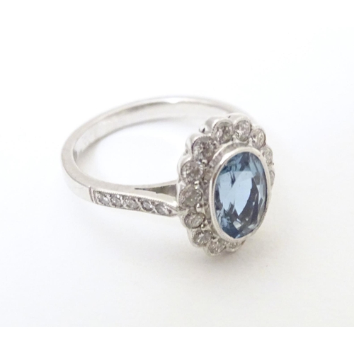 579 - A 9ct white gold ring set with aquamarine coloured oval stone to centre bordered by diamonds with fu... 