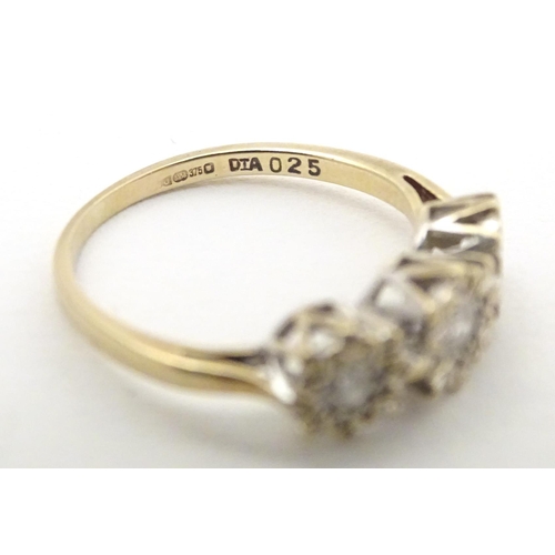 583 - A 9ct gold ring set with a trio of diamonds. Ring size approx. K 1/2