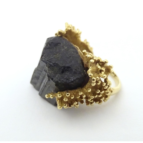 587 - An unusual 18ct gold ring set with black jet coloured hardstone specimen with textured shoulders. Ri... 