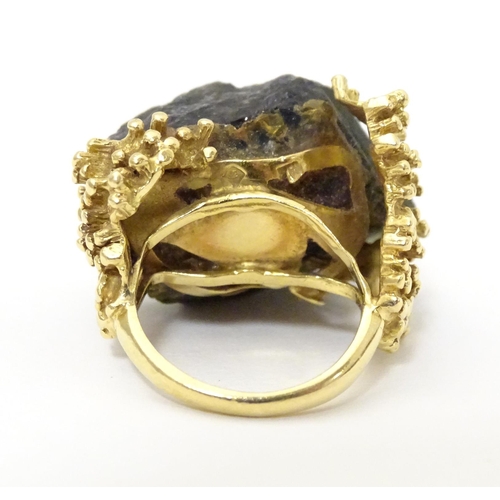 587 - An unusual 18ct gold ring set with black jet coloured hardstone specimen with textured shoulders. Ri... 