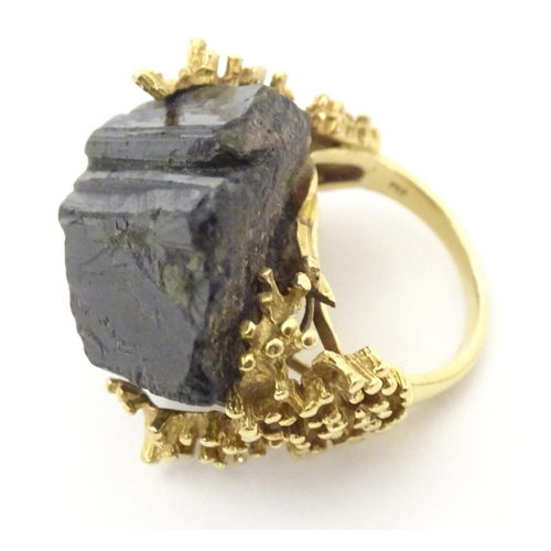 587 - An unusual 18ct gold ring set with black jet coloured hardstone specimen with textured shoulders. Ri... 