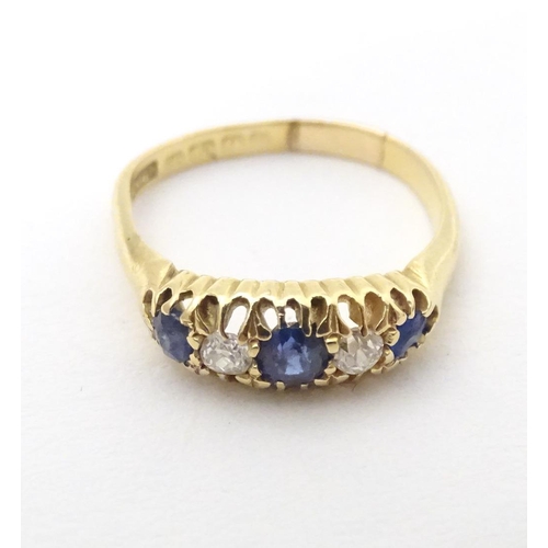 590 - An 18ct gold ring set with diamonds, sapphire and blue stone detail. Ring size approx. N