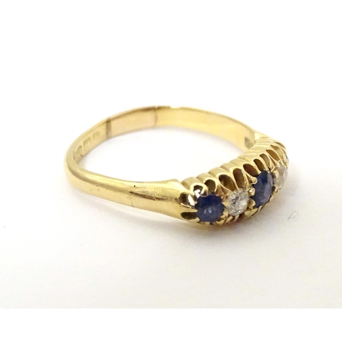 590 - An 18ct gold ring set with diamonds, sapphire and blue stone detail. Ring size approx. N