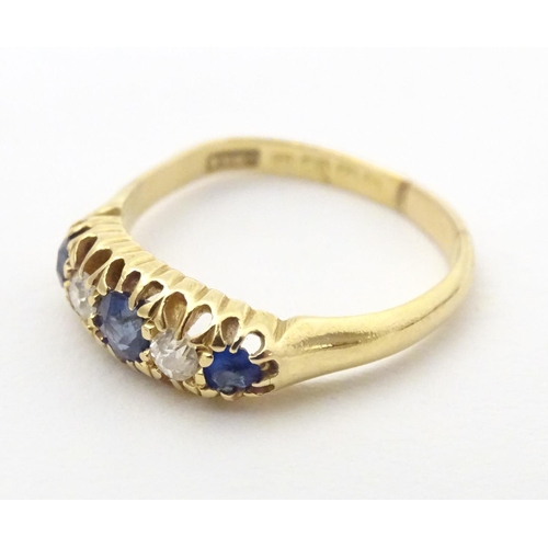 590 - An 18ct gold ring set with diamonds, sapphire and blue stone detail. Ring size approx. N