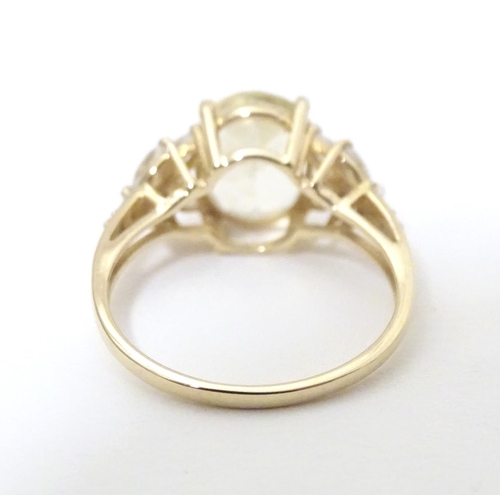 591 - A 9ct gold dress ring set with central oval serenite flanked by four white topaz to each shoulder. R... 