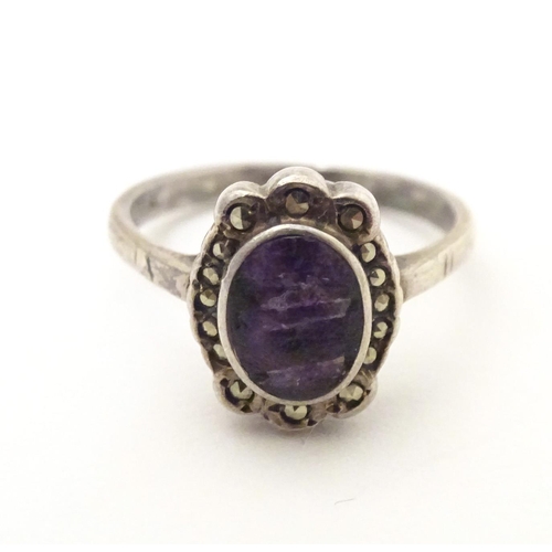 600 - A silver ring set with blue john style cabochon bordered by marcasite. Ring size approx. M 1/2