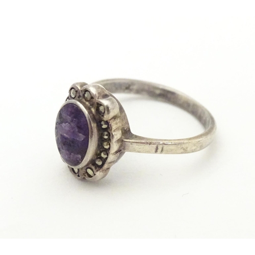 600 - A silver ring set with blue john style cabochon bordered by marcasite. Ring size approx. M 1/2