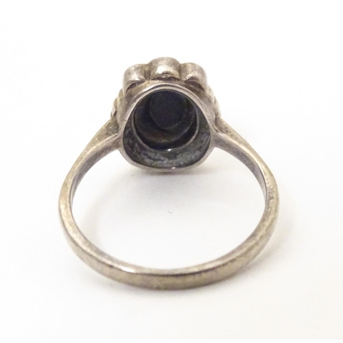 600 - A silver ring set with blue john style cabochon bordered by marcasite. Ring size approx. M 1/2