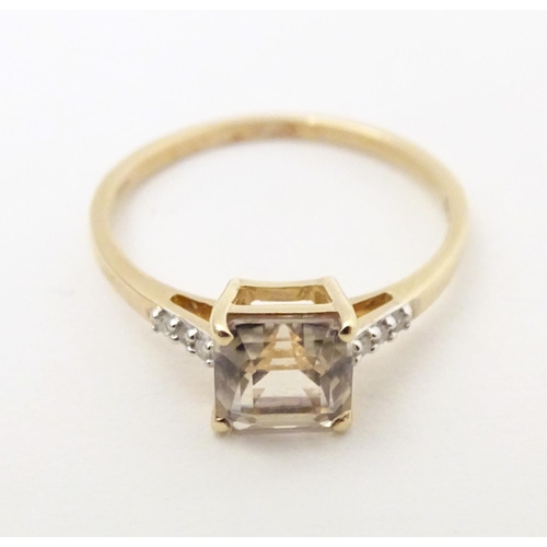 603 - A 9ct gold ring set with central yellow stone (csarite) flanked by three diamonds to each shoulder. ... 