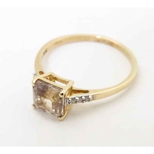 603 - A 9ct gold ring set with central yellow stone (csarite) flanked by three diamonds to each shoulder. ... 