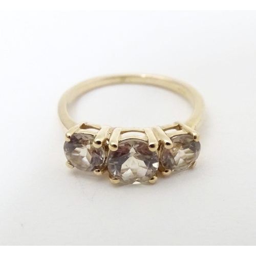 604 - A 9ct gold ring set with a trio of yellow (csarite) stones. Ring size approx. L