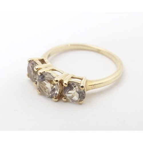 604 - A 9ct gold ring set with a trio of yellow (csarite) stones. Ring size approx. L