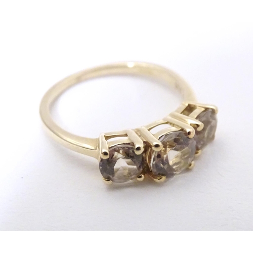 604 - A 9ct gold ring set with a trio of yellow (csarite) stones. Ring size approx. L