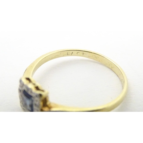 609 - An 18ct gold ring set with central sapphire bordered by diamonds in a platinum setting. Ring size ap... 