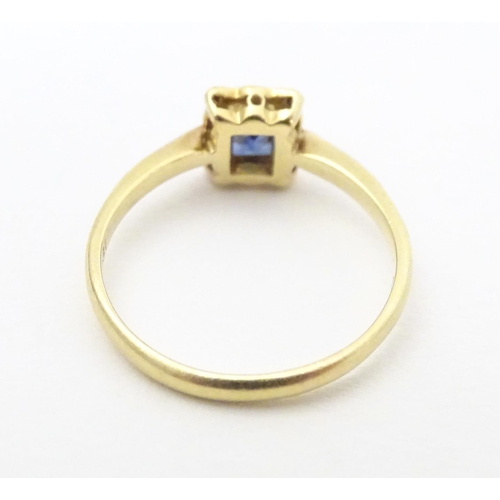 609 - An 18ct gold ring set with central sapphire bordered by diamonds in a platinum setting. Ring size ap... 