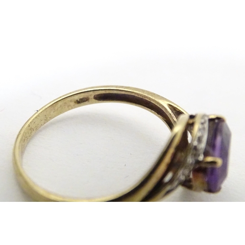 610 - A 9ct gold ring set with central amethyst flanked by diamonds. Ring size approx. R