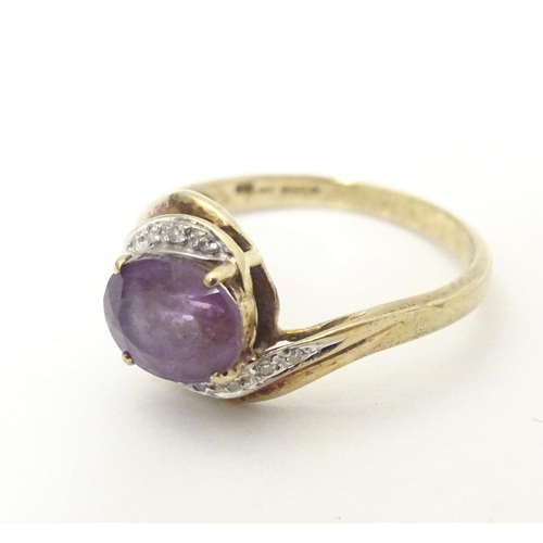 610 - A 9ct gold ring set with central amethyst flanked by diamonds. Ring size approx. R